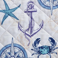 A nautical and coastal designed reversible quilt set for a bed, featuring blue and white nautical patterns, with a light fabric.