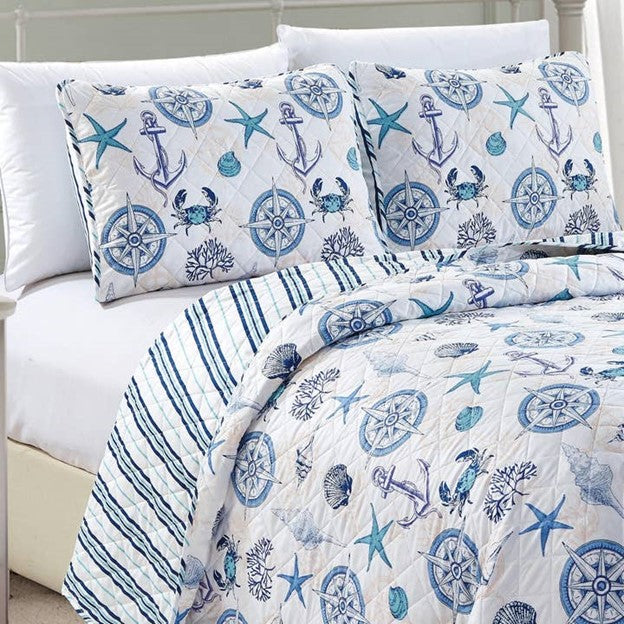 A nautical and coastal designed reversible quilt set for a bed, featuring blue and white nautical patterns, with a light fabric.