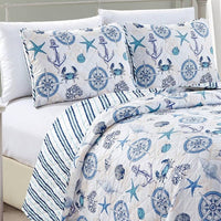 A nautical and coastal designed reversible quilt set for a bed, featuring blue and white nautical patterns, with a light fabric.