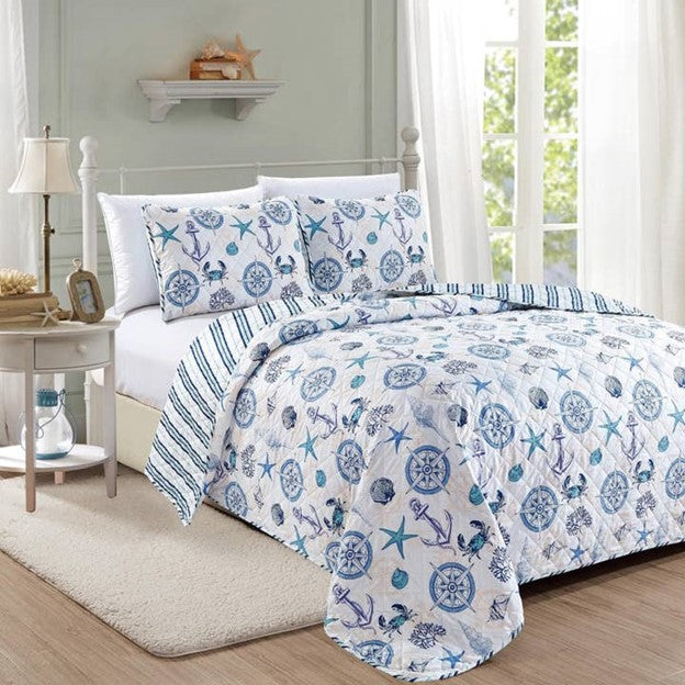 A nautical and coastal designed reversible quilt set for a bed, featuring blue and white nautical patterns, with a light fabric.