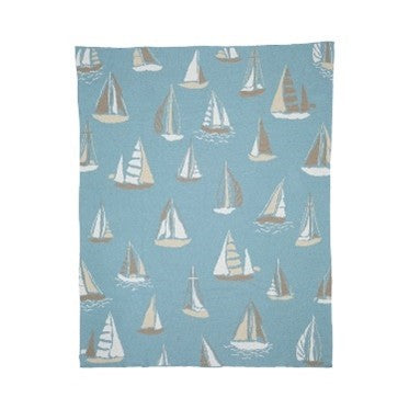 A rectangular light blue throw cotton blanket by In2Green with a nautical sailboat pattern.