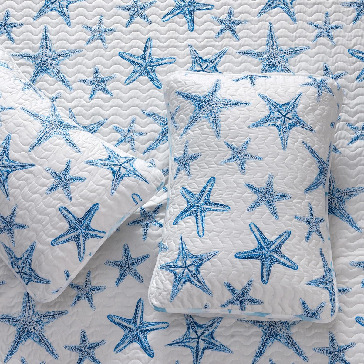 A lightweight quilt set featuring a coastal starfish design in blue on a white background, with two matching pillow shams.  Known as the Trinidad C3 piece Collection.
