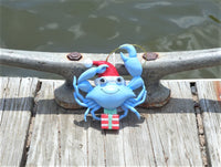 Blue crab nautical Christmas ornament wearing a red Santa hat and holding a gift box on a dock ready to get in the water
