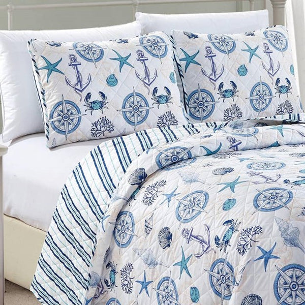 A nautical and coastal designed reversible quilt set for a bed, featuring blue and white nautical patterns, with a light fabric.
