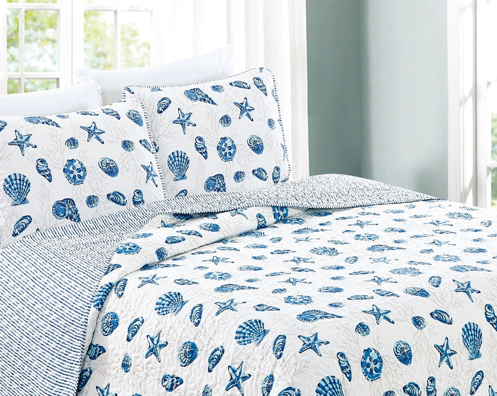 A coastal seashell and star-designed lightweight quilt set for a bed, with a pattern of shore shellfish life including starfish and shells in blue and white tones.