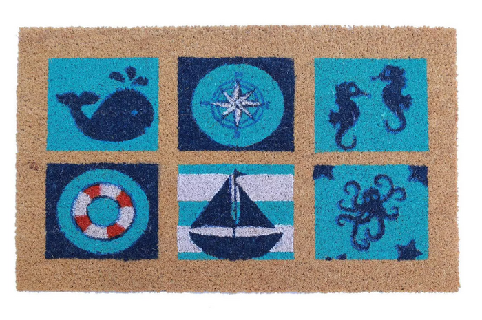 A rectangular coir outdoor door mat with nautical designs including a whale, a lifebuoy, and a sailboat, placed on a doorstep.