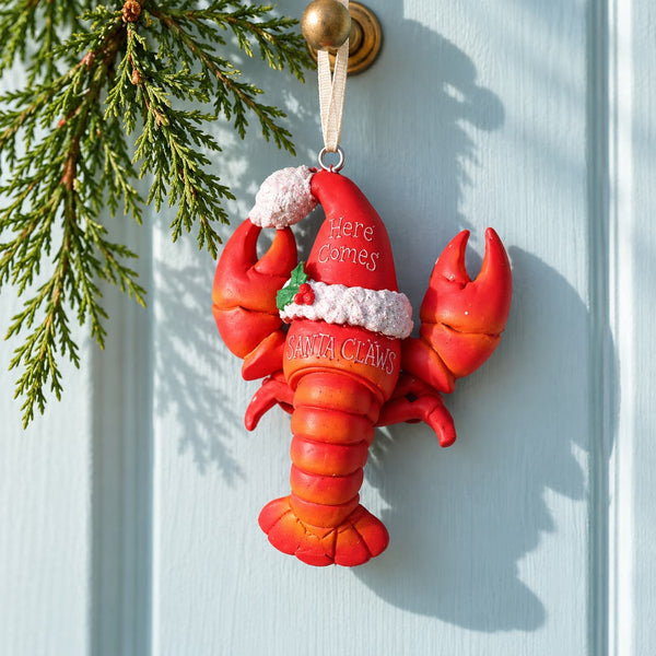 Under The Sea Lobster with sparkly Santa Hat Ornament handing from a door with pine branches.