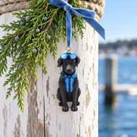 Black dog Christmas ornament with blue goggles and scuba gear hanging from pine branch on a dock