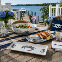 White ceramic serving bowl with blue crab design on a table with 2 crab designed platters
