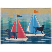 A rectangular high traffic rug with non-skid backing featuring two black labs on red and aqua sail boats, with a predominantly blue ocean background.