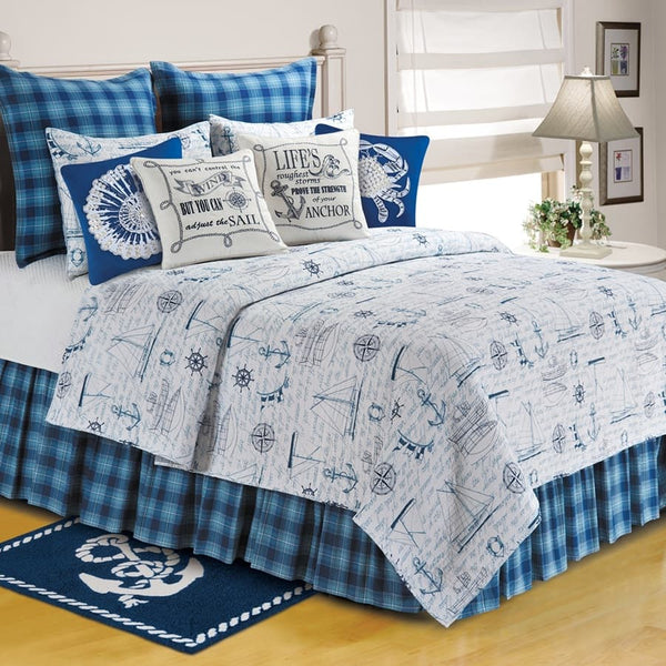 Nautical white quilt with blue sailboats, anchors, and compasses in blue and white with matching pillows.