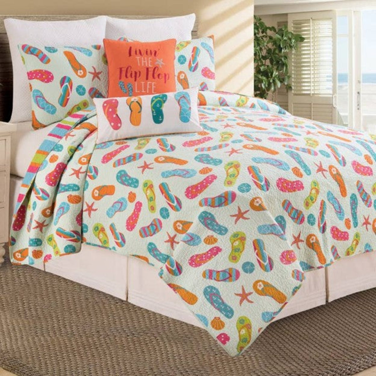 Colorful flip flop patterned bedding set on a bed in a room with a window.