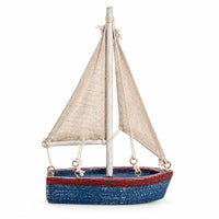 A sailboat ornament with a distressed blue hull, a red stripe, beige canvas sails, and a silver mast.