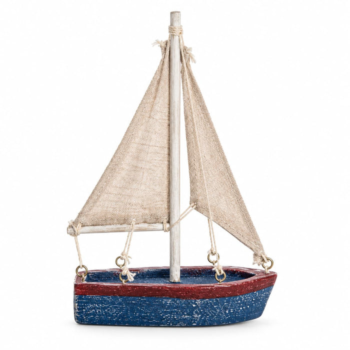 A sailboat ornament with a distressed blue hull, a red stripe, beige canvas sails, and a silver mast.