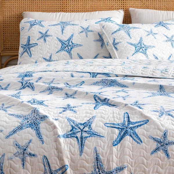 A lightweight quilt set featuring a coastal starfish design in blue on a white background, with two matching pillow shams.  Known as the Trinidad C3 piece Collection.