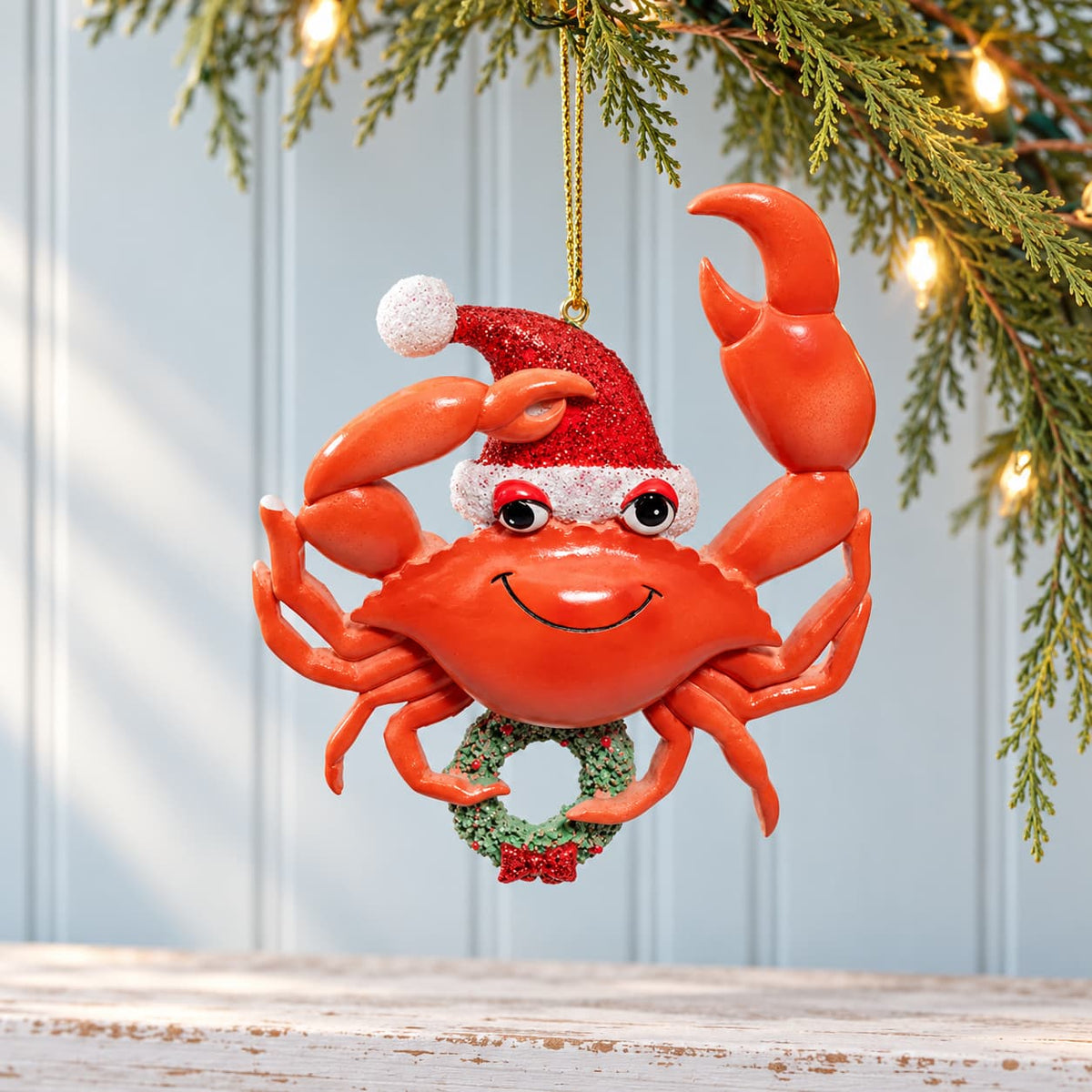 Decorative and Whimsical Red Crab with wreath and sparkly Santa hat Christmas Ornament hanging from a pine branch