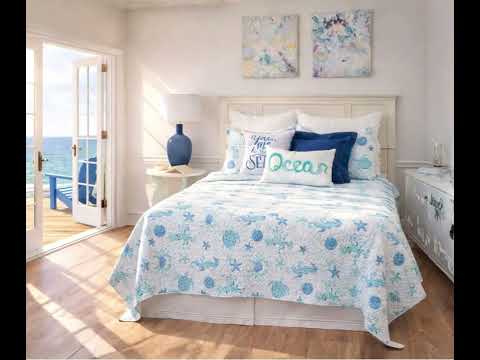 A coastal seascape-designed lightweight quilt set for a bed, with a pattern of marine life including fish and coral in blue and white tones.